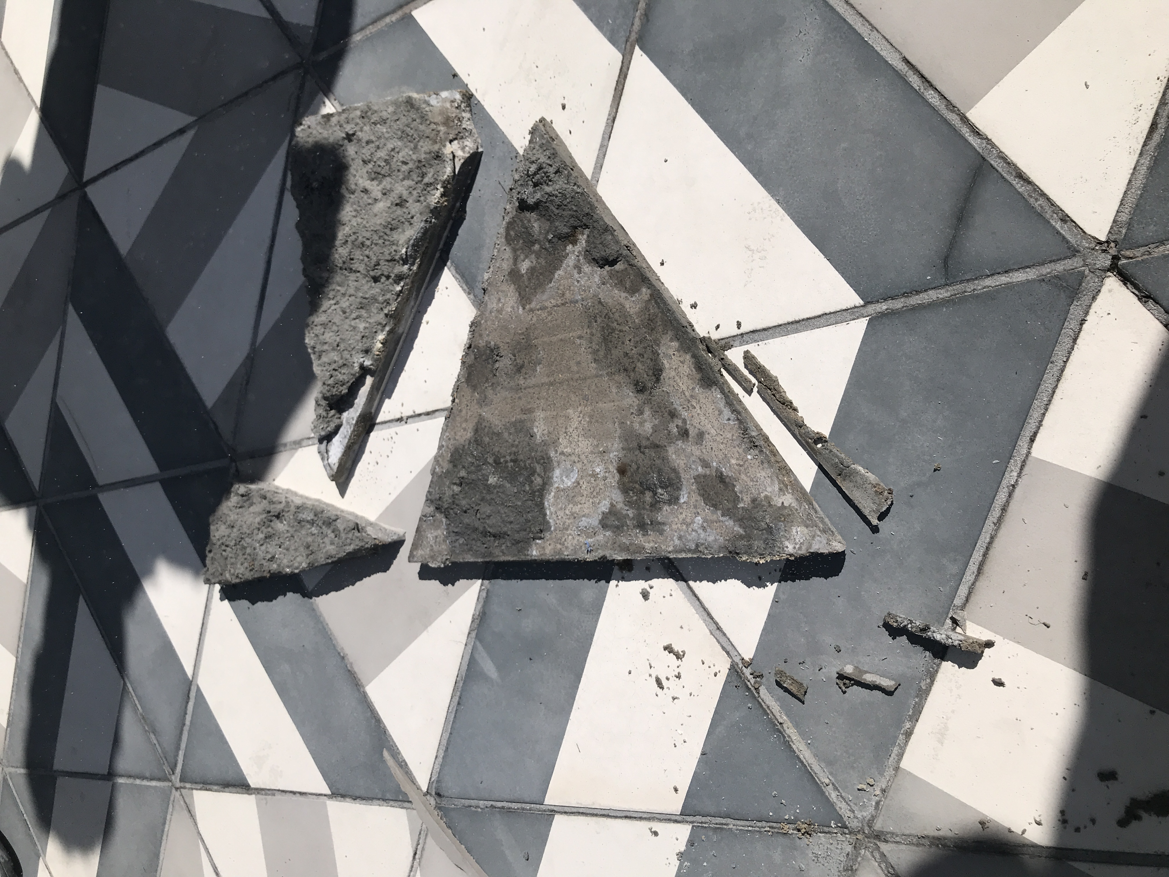 Broken concrete pool deck tile removed from installation showing mortar bed failure and inadequate bond