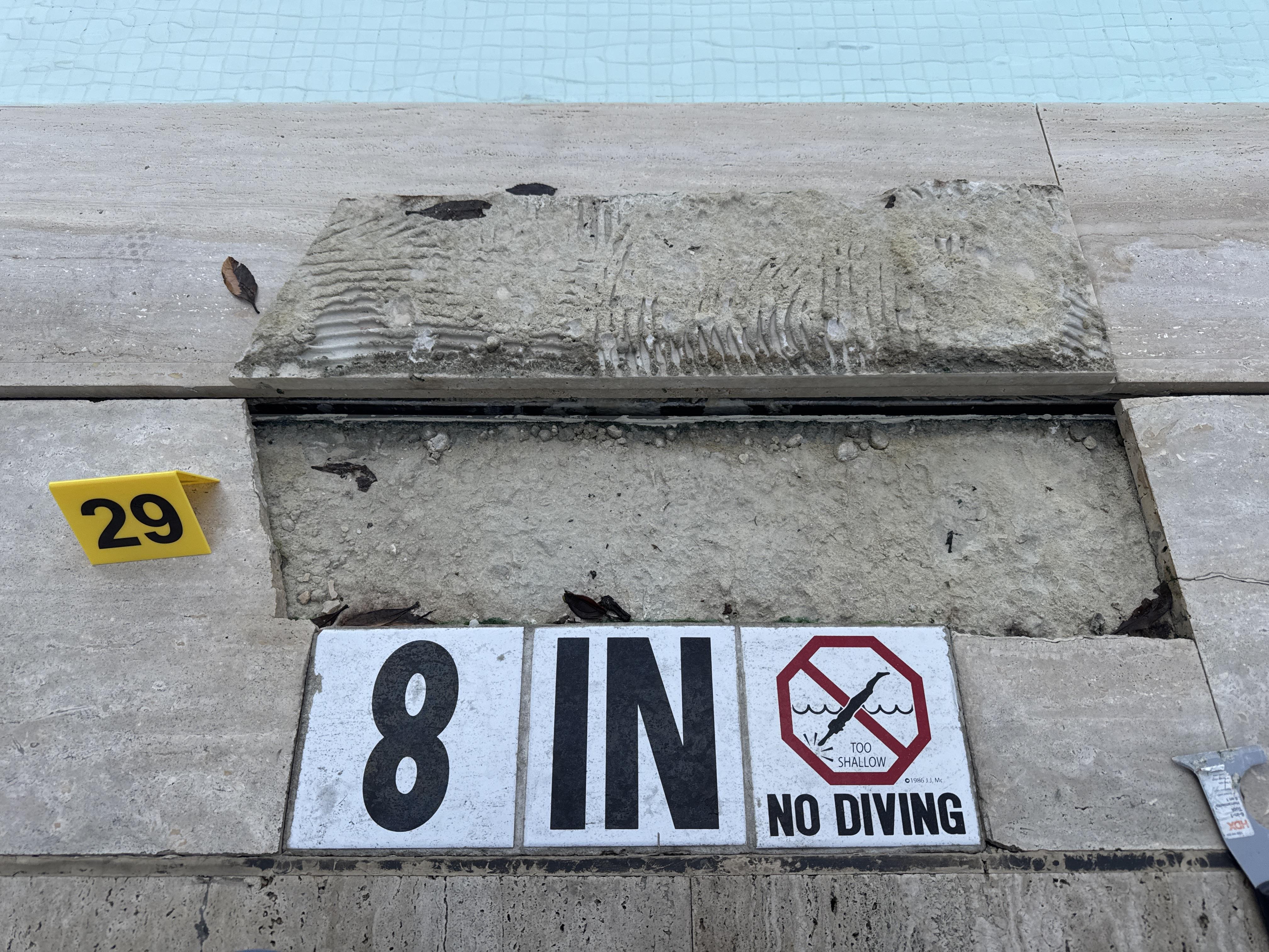 Removed pool deck travertine tile at evidence marker 29 revealing deficient mortar bed condition at hotel pool